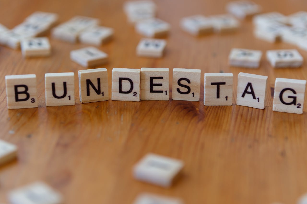 Wooden Scrabble tiles spelling 'Bundestag' on a rustic table, symbolizing German politics.
